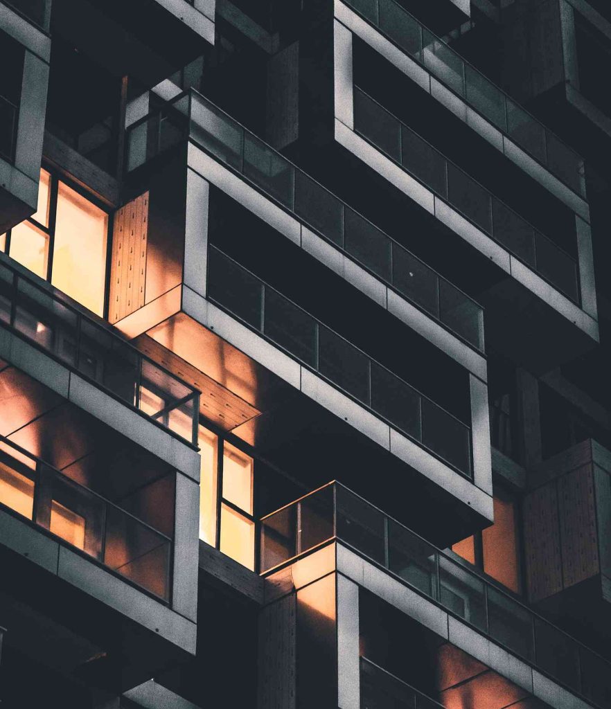 Apartment building facade with illuminated windows and balconies at night.
