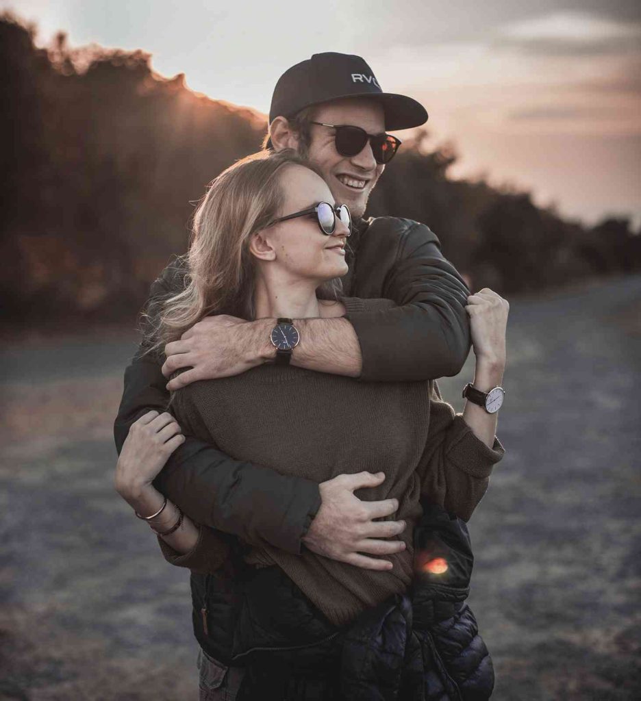 Happy couple embracing outdoors at sunset.