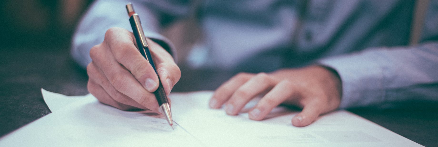 Close-up of hands writing author guidelines on paper for scholarly journal submission.